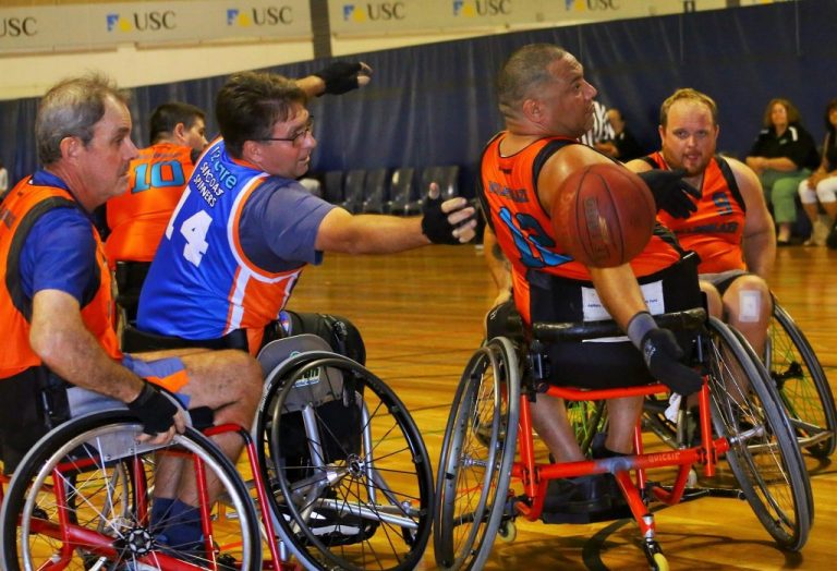 group of male players reaching to grab basketball